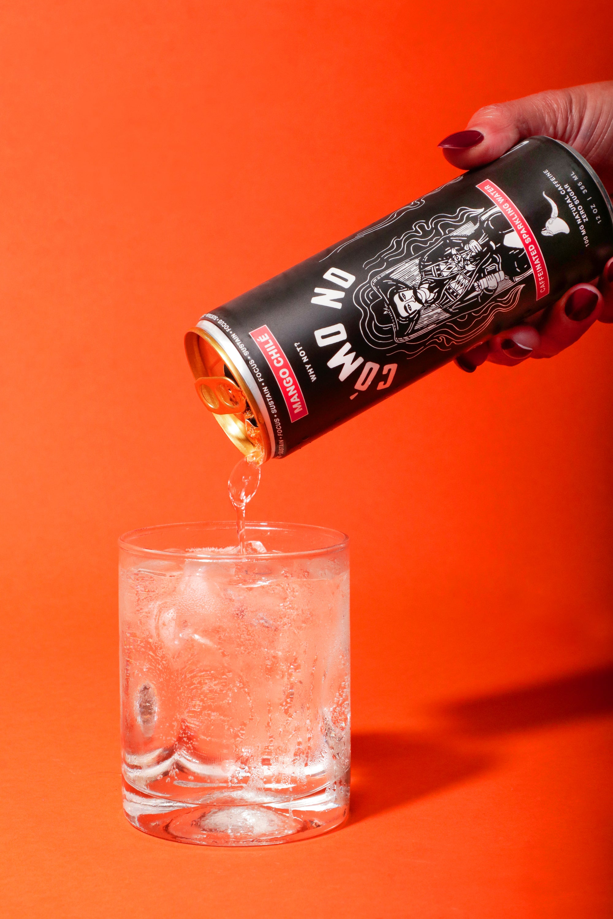 12 Pack Mango Chile energy drink being poured into clear glass with ice against vibrant orange background